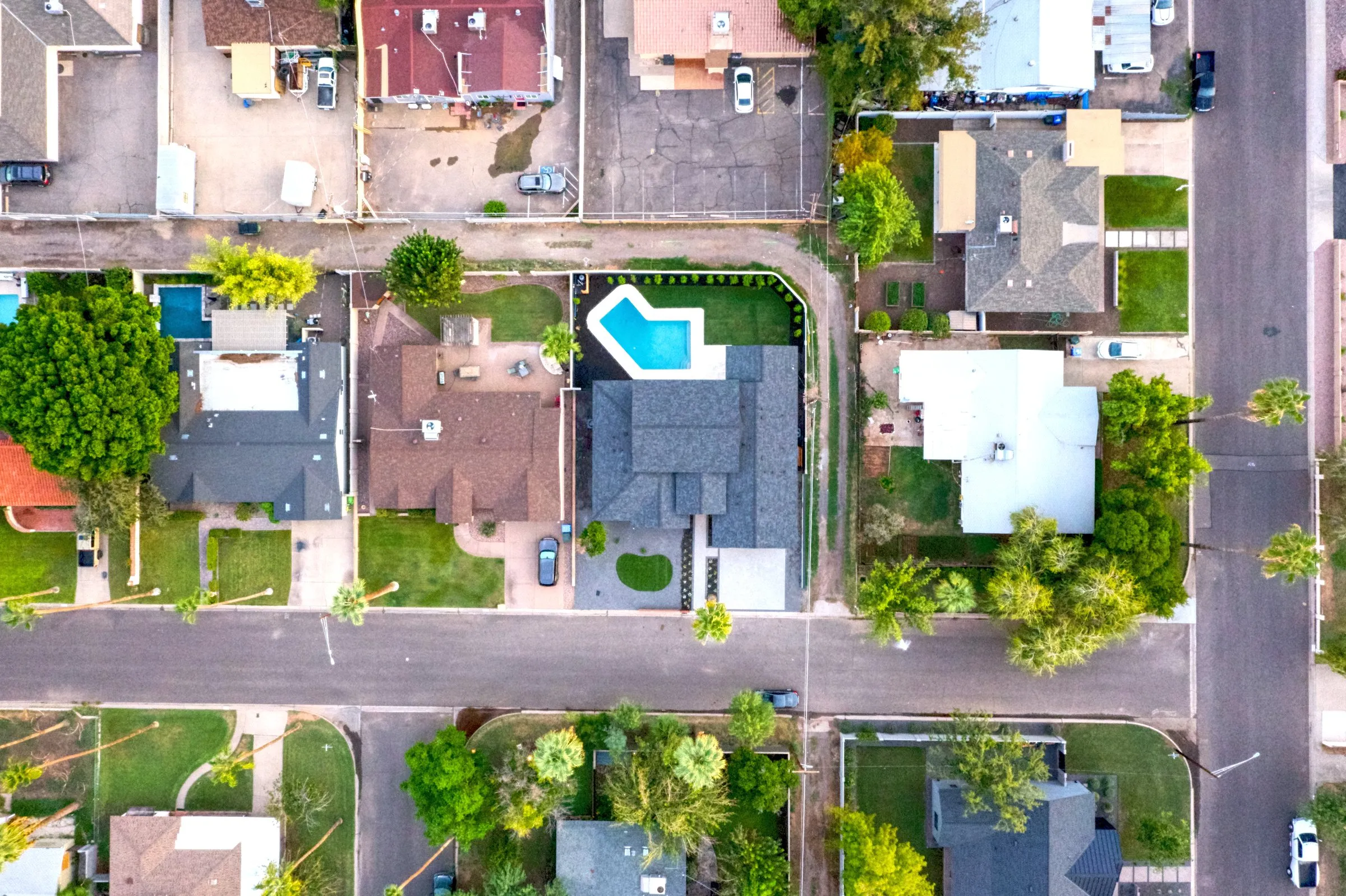 Top-down aerial view of a residential neighborhood grid with a home and small blue pool.